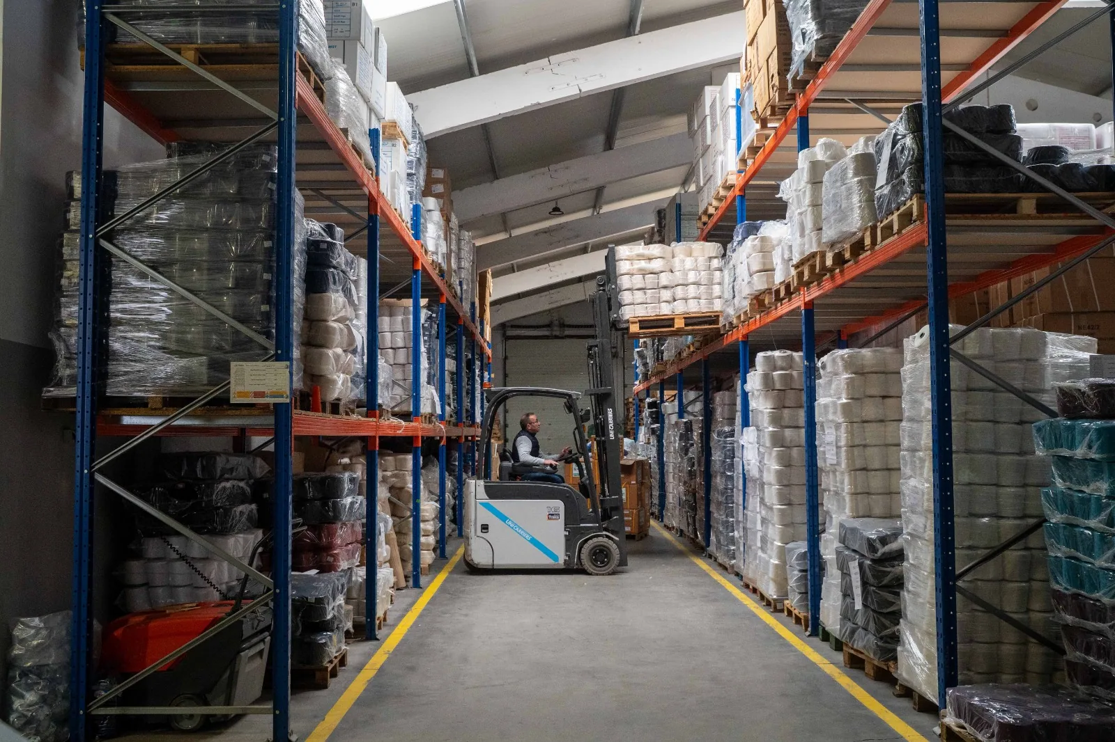 Corredor do armazém da Matema, com estantes de produto e um empilhador.